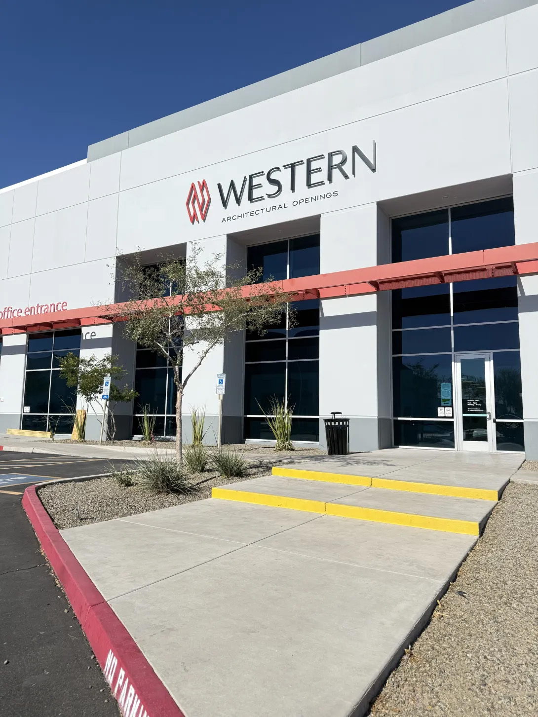 Rebranded Western Architectural Openings building exterior with signage, red awning, and concrete walkway leading to the office entrance.