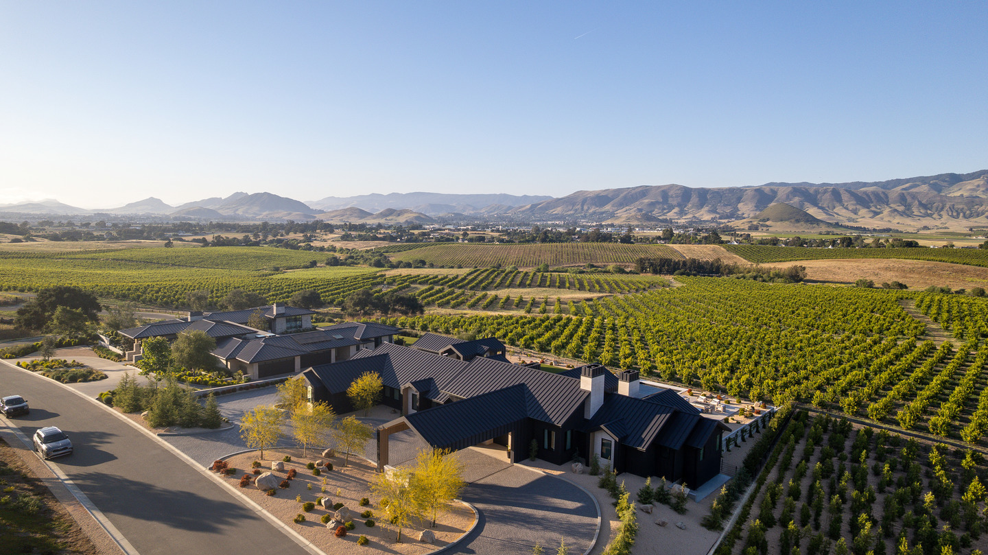 Aerial view of a contemporary San Luis Obispo residence surrounded by vineyard rows and  rolling California hills.