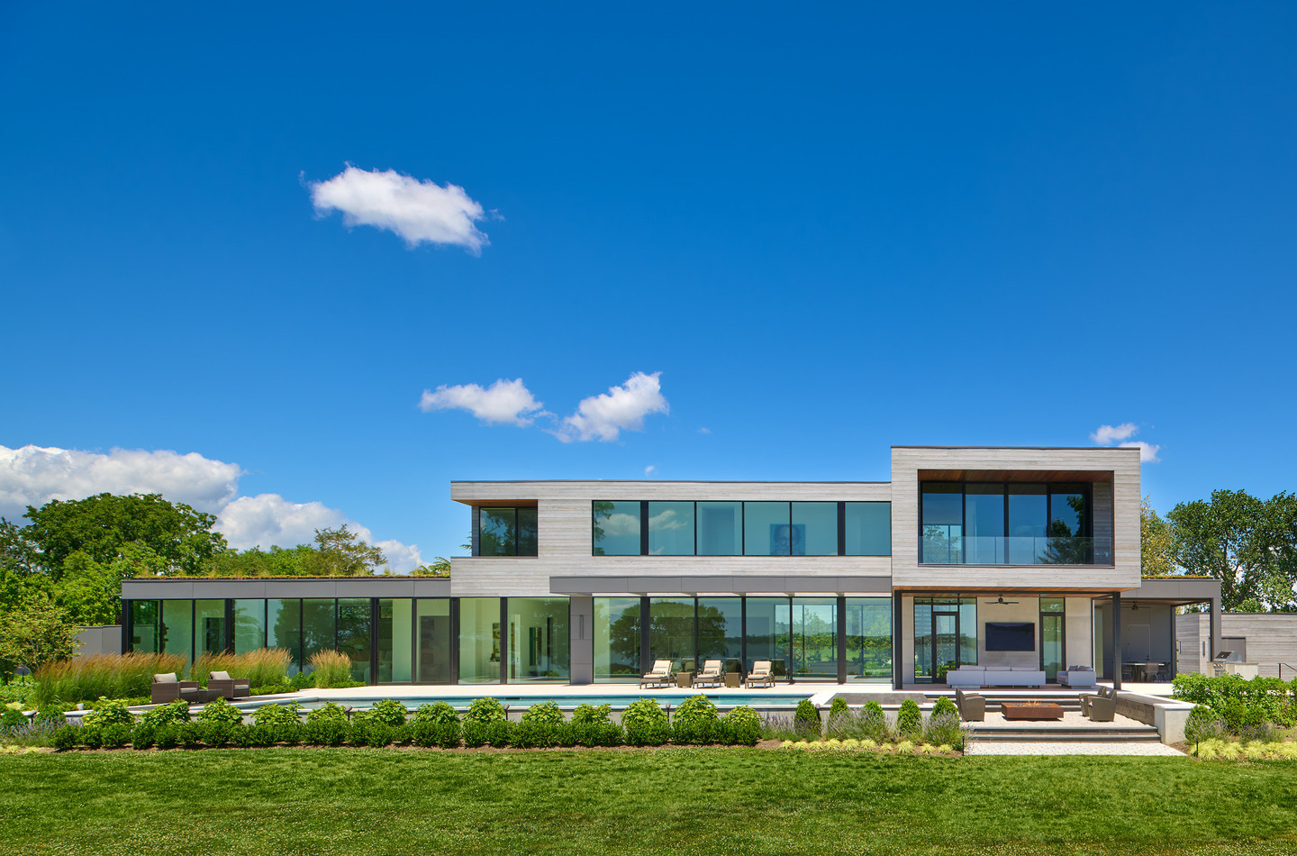 Modern two-story home featuring expansive Western Architectural Openings Classic Collection windows and doors overlooking a landscaped backyard and pool.