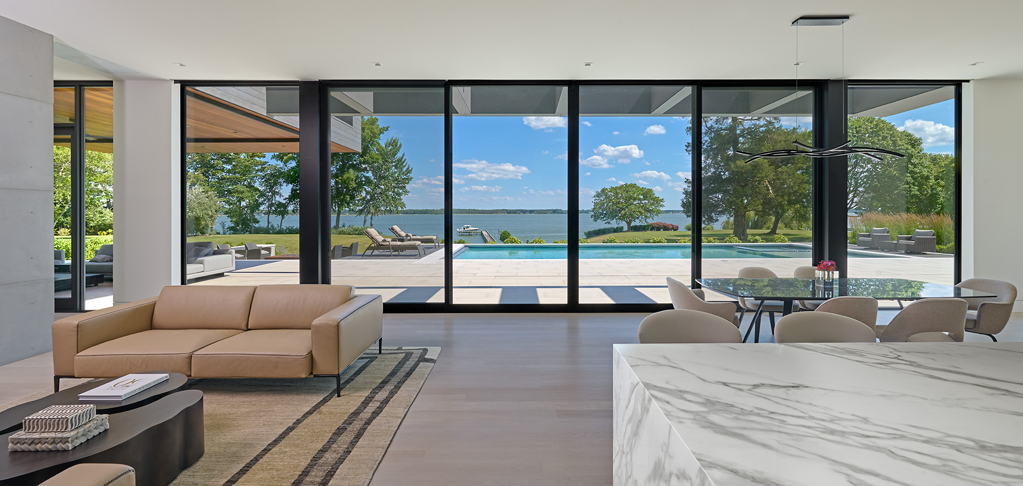 Modern living space with expansive glass doors overlooking a pool and waterfront landscape.