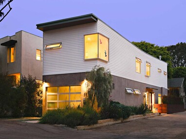 A front view of the two-story prefabricated home with fixed and operable windows and a frosted glass garage door.
