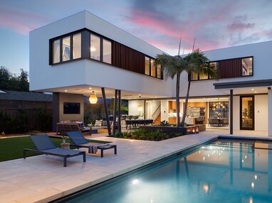 An outside view of the home with a wall-length pocketing multi-slide door on the first floor and numerous windows on the second floor.