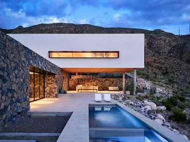 This Texas home uses volcanic rock basalt and granite on its façade to blend in with the mountainside and large panels of glass to frame mountain views.