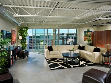 A view of the living room with a large multi-slide door behind the couch leading to a balcony.