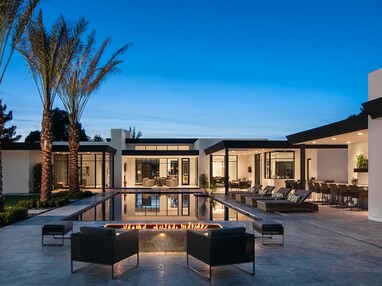 A front view of a glassy home that eliminates the barrier between the interior and pool outside.