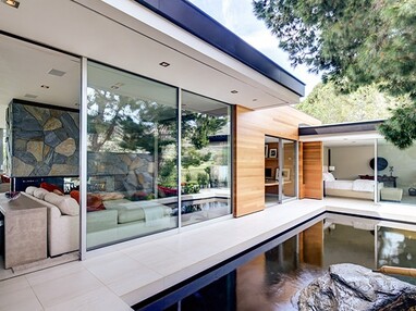 The open sliding glass doors connect indoor spaces to the courtyard with a man-made pond.