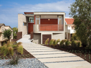 A front view of the two-story home with wooden doors and panes of glass surrounding the front and garage door.