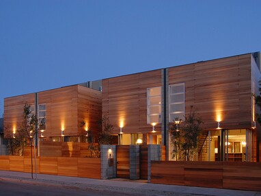 The front view of a large, wood paneled home with sliding glass doors on the first floor.