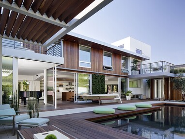 A view of the home’s glass-embracing façade with numerous sliding glass doors and windows.