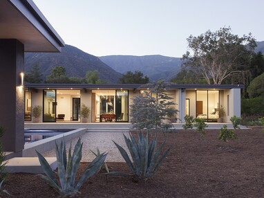 A view of the home’s façade with several open sliding glass doors connecting to the backyard.