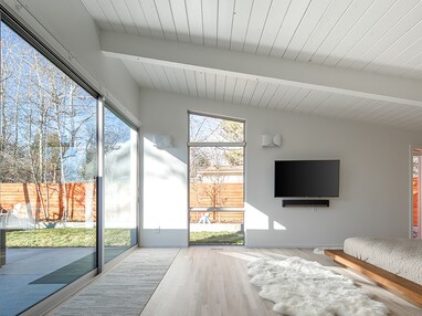 A large sliding glass door alongside a large custom window opens the bedroom to the patio while fixed windows allow even more natural light into the room.