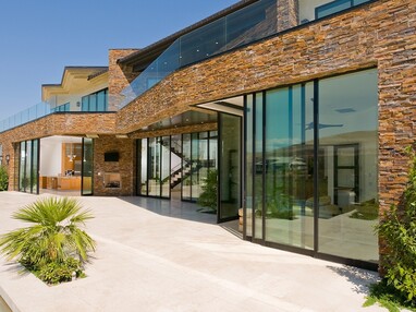 A front view of the two-story showroom with numerous multi-slide doors opening the home to the desert.