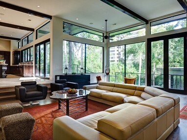 A rustic living room is surrounded by fixed windows and hinged doors, adding a modern touch and natural light.