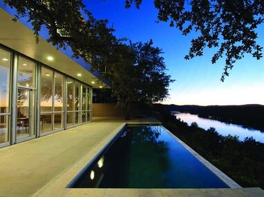 A view of the home’s complete glass wall that provides views of the pool and river outside.