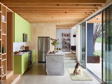 A large, open multi-slide door with a dog sitting in front of it connects the kitchen to the backyard.