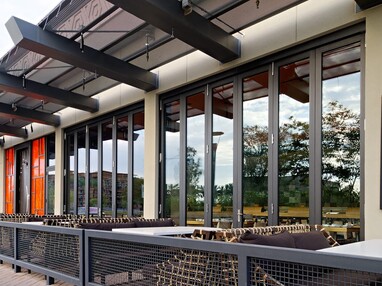 Floor-to-ceiling bi-fold doors connect the interior of the restaurant to the outside dinging tables.