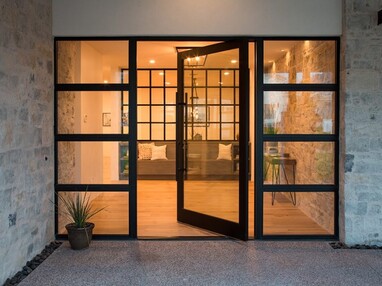 An extra wide pivot door is flanked by two gridded windows.