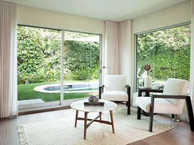 The lounge area opens to the green backyard through a large sliding glass door.