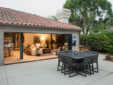 Open Series 9500 Bi-Fold Doors merge the indoor dining area with an outside sitting area.