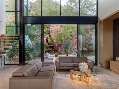 The sitting room features a 21-foot-wide multi-slide door opening to an outdoor seating area next to the red rock.