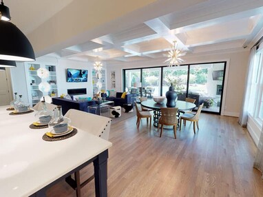 An indoor living and dining room has floor-to-ceiling multi-slide glass doors that lead outside.