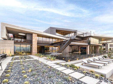 A view from the back of the three-story house with large multi-slide doors overlooking the gravel landscaping in the backyard.