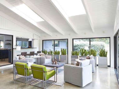 A view of the seating area in the enclosed sunroom surrounded by sliding glass doors.