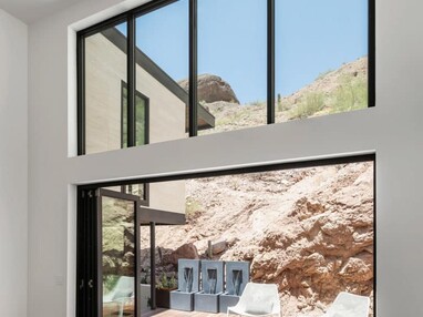 An open bi-fold door connects the dining area to an outdoor seating area right by mountainous terrain.