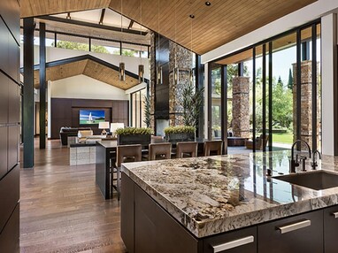 Floor-to-ceiling multi-slide doors and clerestory windows bathe the kitchen and dining area in light.
