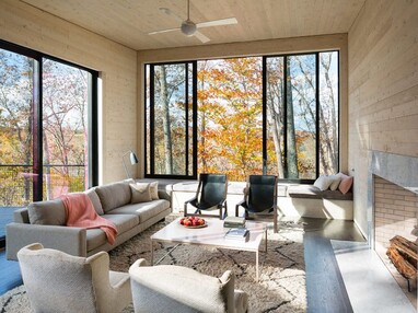 Huge moving walls of glass frame beautiful views of the Virginia countryside in this cozy living room.