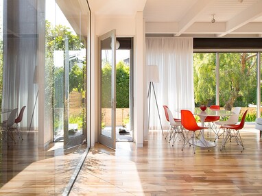 A hinged door opens to the backyard next to walls of glass.