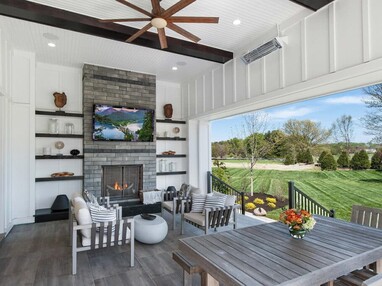 An outdoor seating area is connected to the indoors and colorful backyard by a floor-to-ceiling multi-slide glass door.