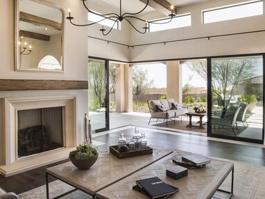 A cozy indoor living room transitions to an outdoor living area, uninterrupted by tall multi-slide glass doors.
