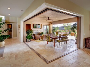 A pocketed 90-degree multi-slide glass door connects an outdoor living space to the indoors.