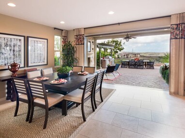 An indoor dining area is connected to an outdoor seating area via pocketed multi-slide glass doors.