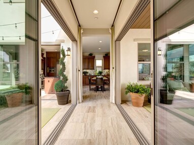 Two floor-to-ceiling multi-slide doors meet in a hallway to connect two outdoor living spaces.