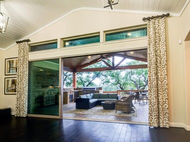 The inside of a home is opened to an outdoor living space through multi-slide glass doors.