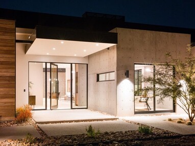 The front of a modern home with concrete and wood planking and a glassy entrance with an open Series 980 pivot entry door.
