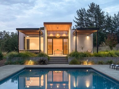 A front view of the guest house during dusk with the pool in the foreground.