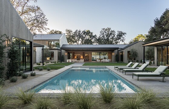 A courtyard with a pool and lounge chairs is surrounded by a modern home with large glass doors and windows. 