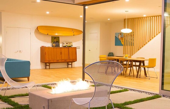 A large 90-degree multi-slide door opens to connect the interior space to the outdoor patio with a fireplace.