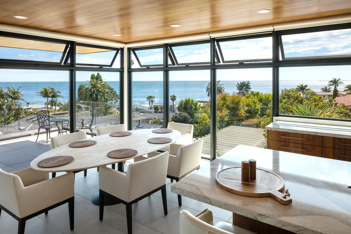 Ocean-view dining room in a Pismo Beach residence with floor-to-ceiling windows and multiple open awning windows.
