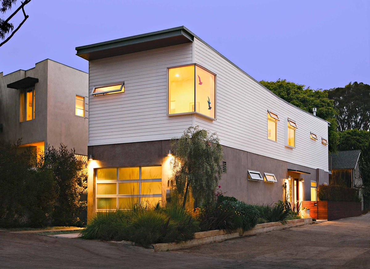 A front view of the two-story prefabricated home with fixed and operable windows and a frosted glass garage door.