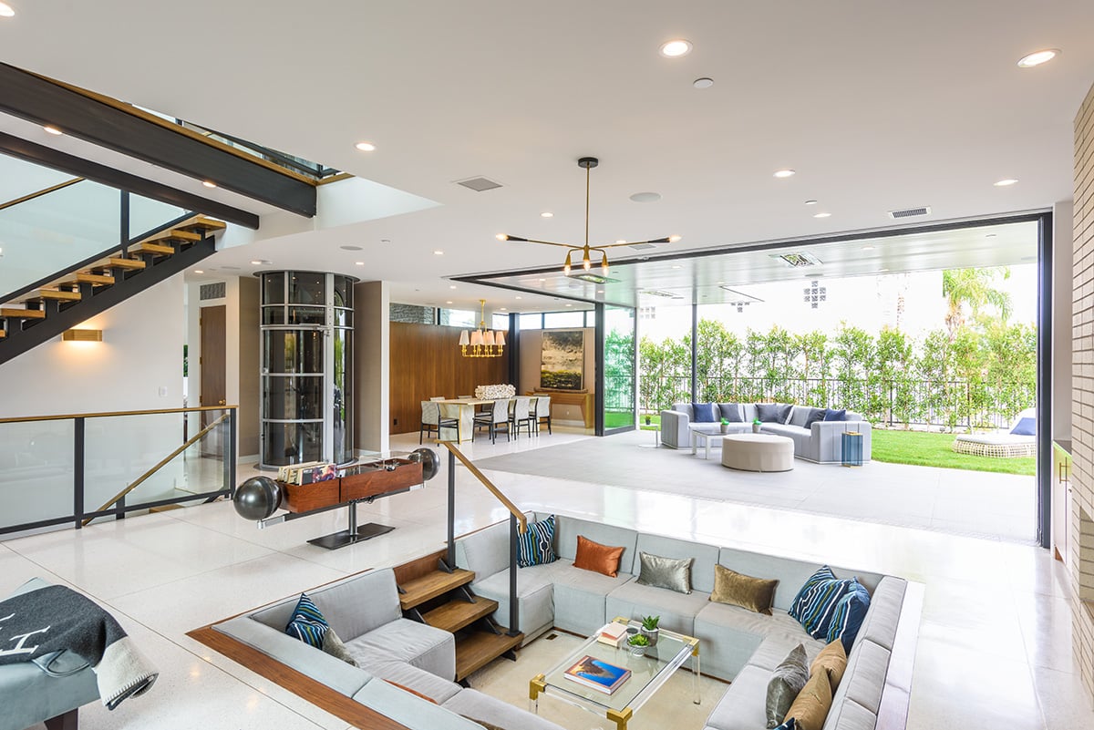 A 90-degree multi-slide door connects the indoor conversation pit to an outdoor seating area.