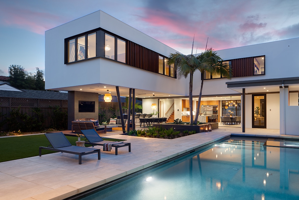 An outside view of the home with a wall-length pocketing multi-slide door on the first floor and numerous windows on the second floor.