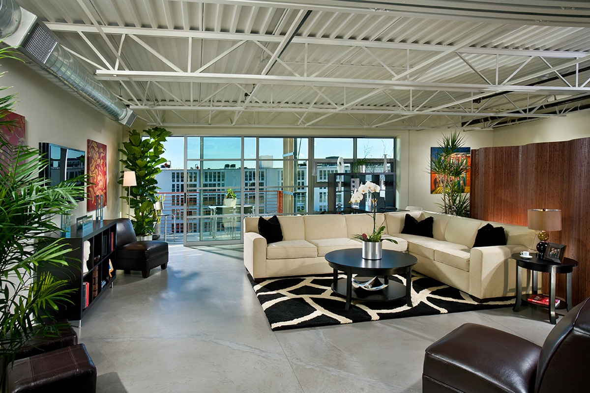A view of the living room with a large multi-slide door behind the couch leading to a balcony.