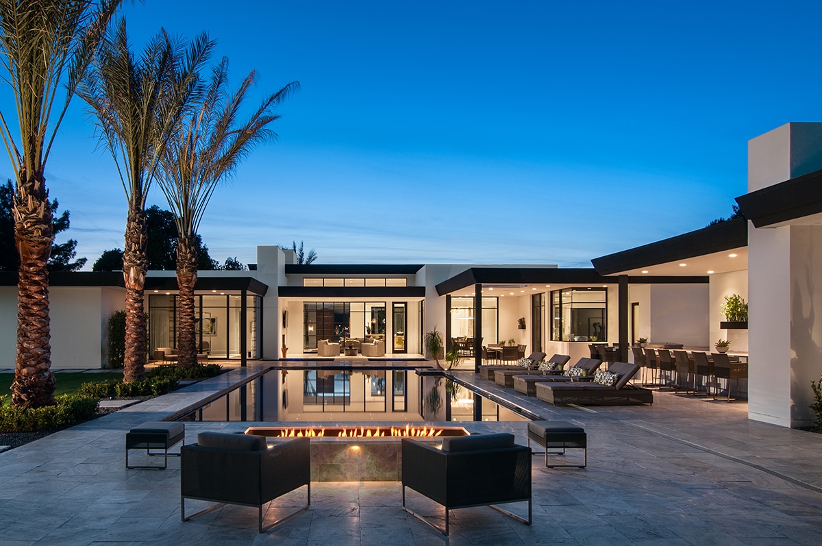 A front view of a glassy home that eliminates the barrier between the interior and pool outside.