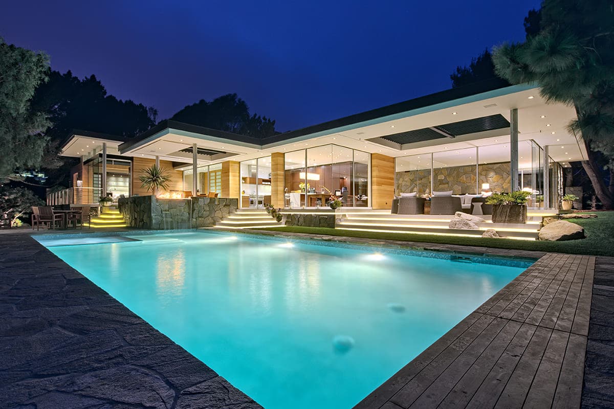 Western Window Systems’ doors offer the illusion of this modern home with wood paneling being a house of almost completely glass.