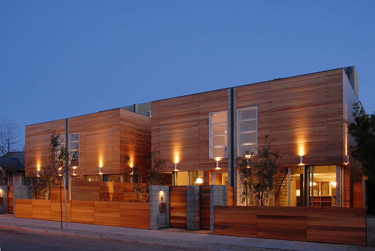 The front view of a large, wood paneled home with sliding glass doors on the first floor.