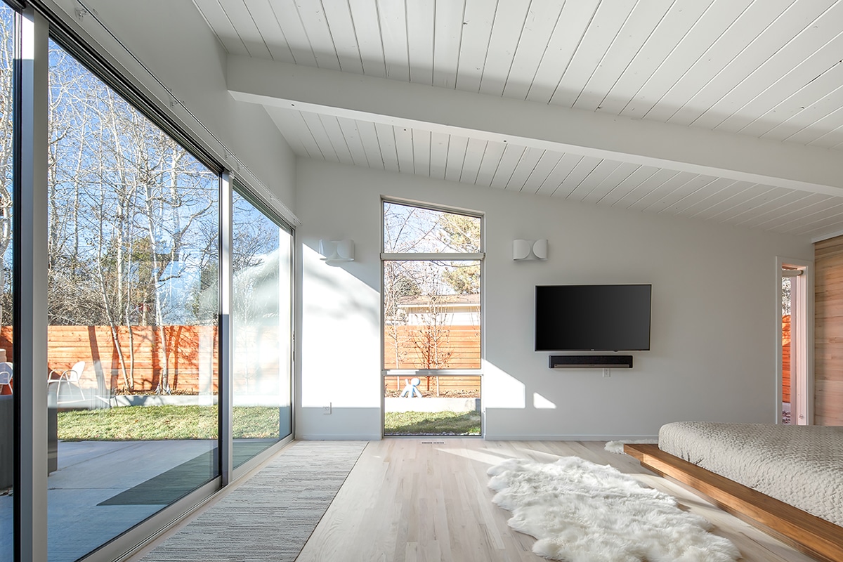 A large sliding glass door alongside a large custom window opens the bedroom to the patio while fixed windows allow even more natural light into the room.